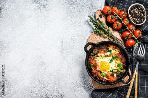 Breakfast with Fried eggs, tomatoes. Shakshuka in pan. Turkish  traditional dishes. Gray background. Top view. Copy space