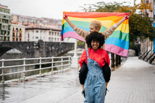 Two women carrying a LGTB flag at street photo