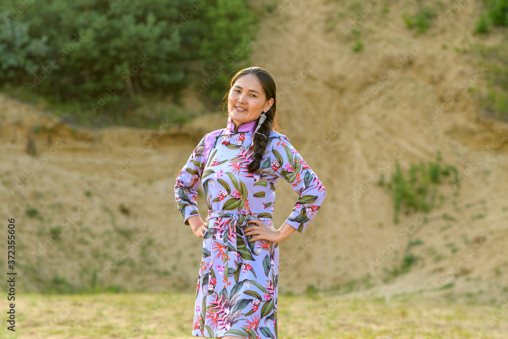 Beauty Mongolian Woman On Gobi Desert With Traditional Mongolian Clothing (Deel). Sunset Landscape With Happy Woman Beauty Mongolian Woman On Gobi Desert With Traditional Mongolian Clothing (Deel). Sunset Landscape With Happy Woman