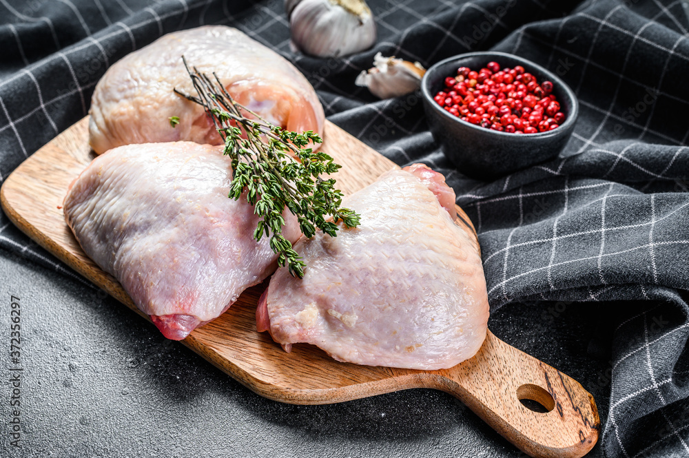 Fresh chicken thigh with skin on cutting board, organic meat. Black background. Top view - obrazy, fototapety, plakaty 