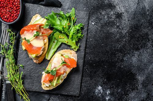 Toasts with avocado and smoked salmon.  Black background. Top view.  Copy space