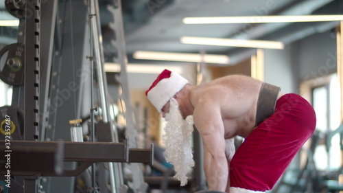 Active fitness man doing deadlift at gym. Man in santa costume making workout