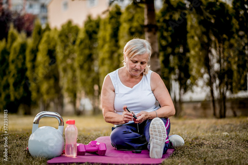 Senior woman with diabetes checking her blood glucose using  glucose meter
