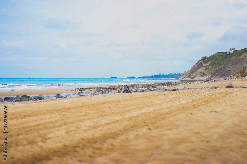 Beach sand rocks and ocean waves against blue coastal skyline