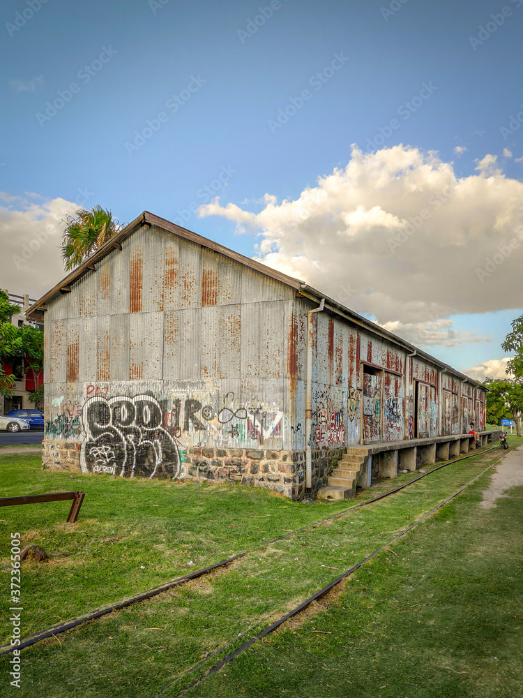 Una bodega de lámina abandonada sobre las vías del tren en Colonia del Sacramento, Uruguay y un cielo con nubes como fondo. Una bodega de lámina abandonada sobre las vías del tren en Colonia del Sacramento, Uruguay y un cielo con nubes como fondo.
