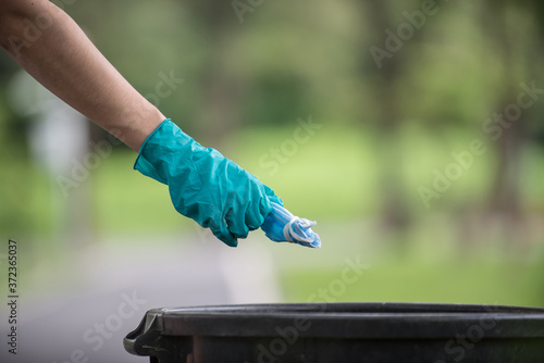 Close-up of a hand, mask and trash bin
