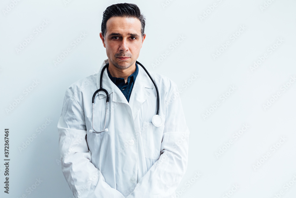 Black haired doctor wearing white coat and stethoscope looking at camera, on white background. Medicine concept