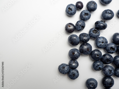 Blueberries spread on a white plane.