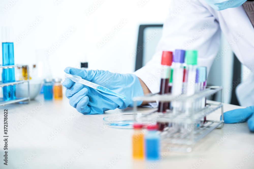 Doctor hold the pipette and drop the blue chemical liquid into a petri dish for research and analysis for treating viral and bacterial illness in a laboratory Doctor hold the pipette and drop the blue chemical liquid into a petri dish for research and analysis for treating viral and bacterial illness in a laboratory