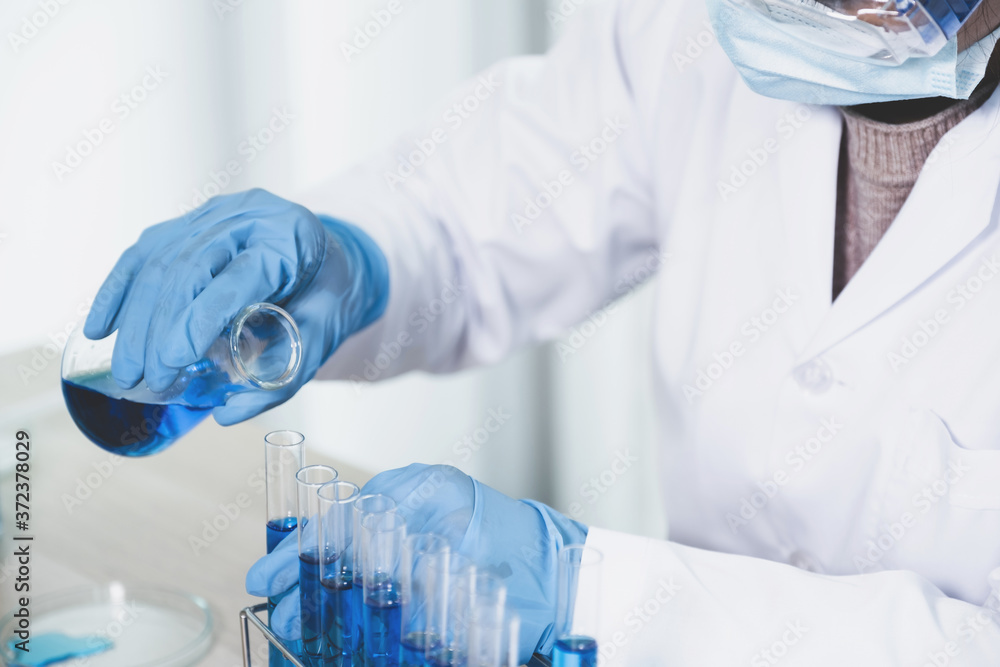 Scientists hand hold a glass filled with blue chemical liquid for research and analysis in a laboratory Scientists hand hold a glass filled with blue chemical liquid for research and analysis in a laboratory