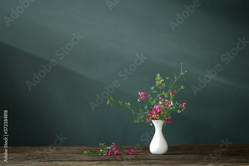 pink summer flowers on wooden table on dark background