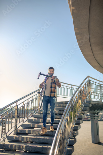 Smiling man carrying bike down city stairs