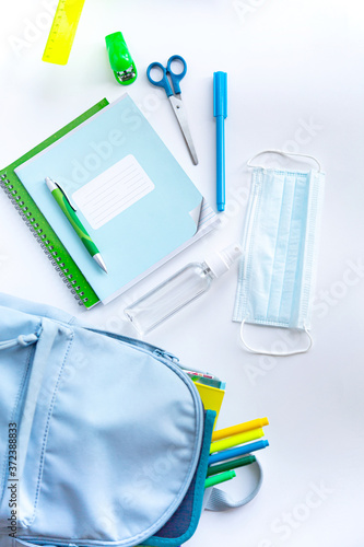 Back to school after coronavirus pandemic. Backpack, stationery, antiseptic, face mask on a white background. 