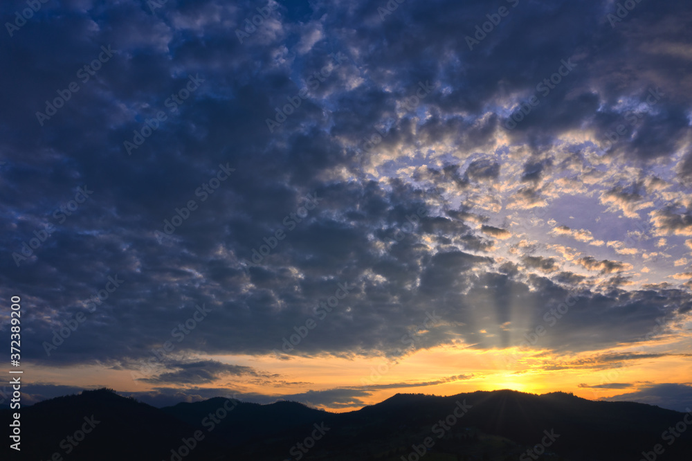 Silhouette of mountains against the background dramatic of the shining sun with beautiful clouds Silhouette of mountains against the background dramatic of the shining sun with beautiful clouds