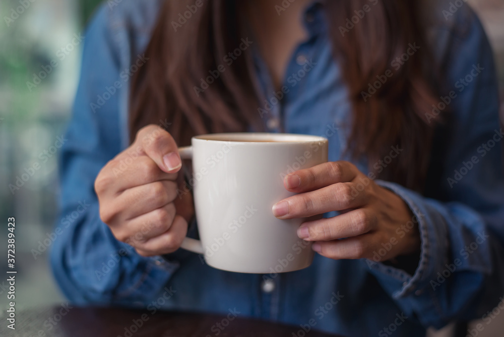 Closeup hand of womale holding a coffee cup in the cafe add the filter retro color tone., How to lifestyle of adult businesswoman in the weekend activity relaxing with the coffee drinking concept. Closeup hand of womale holding a coffee cup in the cafe add the filter retro color tone., How to lifestyle of adult businesswoman in the weekend activity relaxing with the coffee drinking concept.