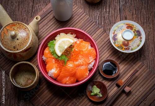 Delicious Donburi or Japanese rice bowl topped Sashimi Salmon Roe and Fish eggs on Bamboo table.