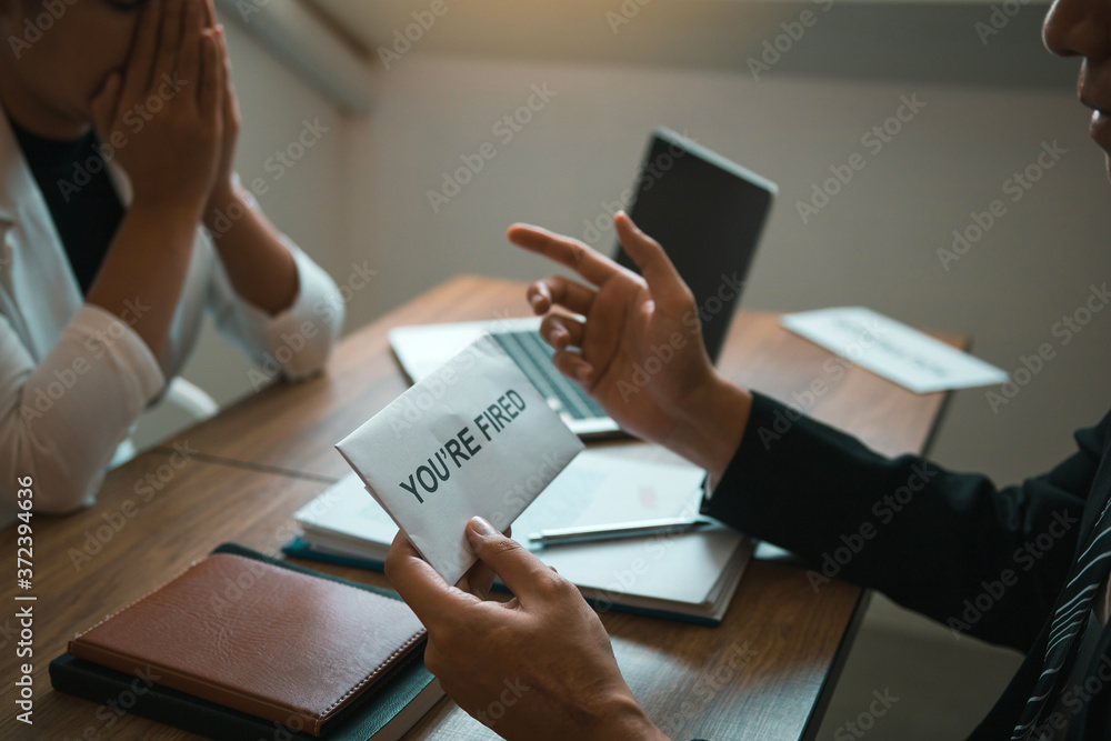 Male manager is talking or explaining about having to dismiss the employee while being handed out a resignation envelope to the employee. Male manager is talking or explaining about having to dismiss the employee while being handed out a resignation envelope to the employee.