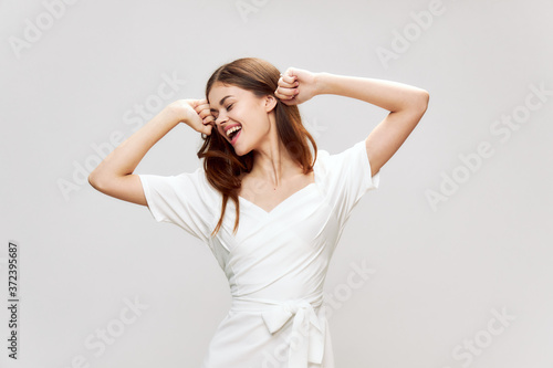 Woman in white dress holds hands near face smile emotions fun studio 