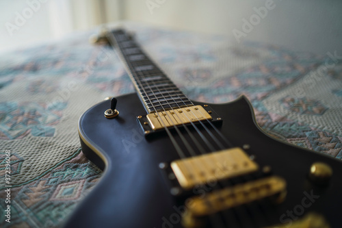 Guitarra negra y dorada sobre una cama