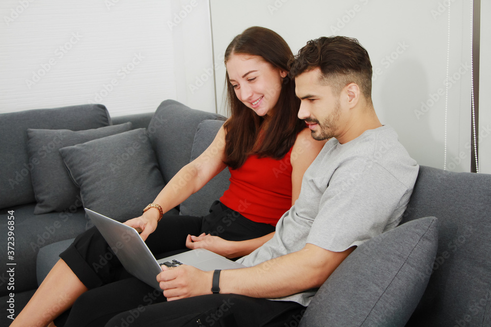 Obraz premium Smiling Caucasian Couple love relaxing and funny in online movie with laptop in social media technology on sofa in living room. Work from home and Married family lifestyle on holiday Concept.