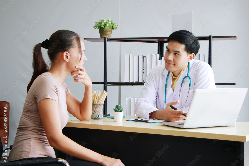 Fototapeta premium Young Asian male psychiatrist is specialist in psychiatry Caucasain female Patient is smiling together for therapy and talking for encourage with laptop in Clinical treatment for emotional symptoms.
