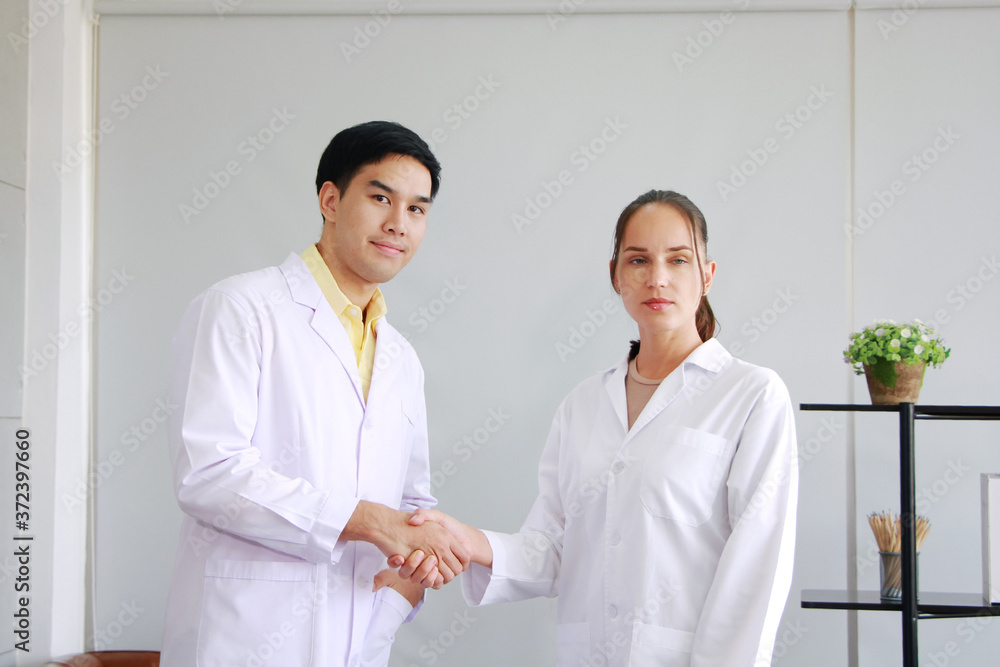 Smiling teamwork of Professional Asian man and Caucasian female Psychiatrist or neurologist doctor is holding hands together in clinical office. Healthcare and technology concept Smiling teamwork of Professional Asian man and Caucasian female Psychiatrist or neurologist doctor is holding hands together in clinical office. Healthcare and technology concept