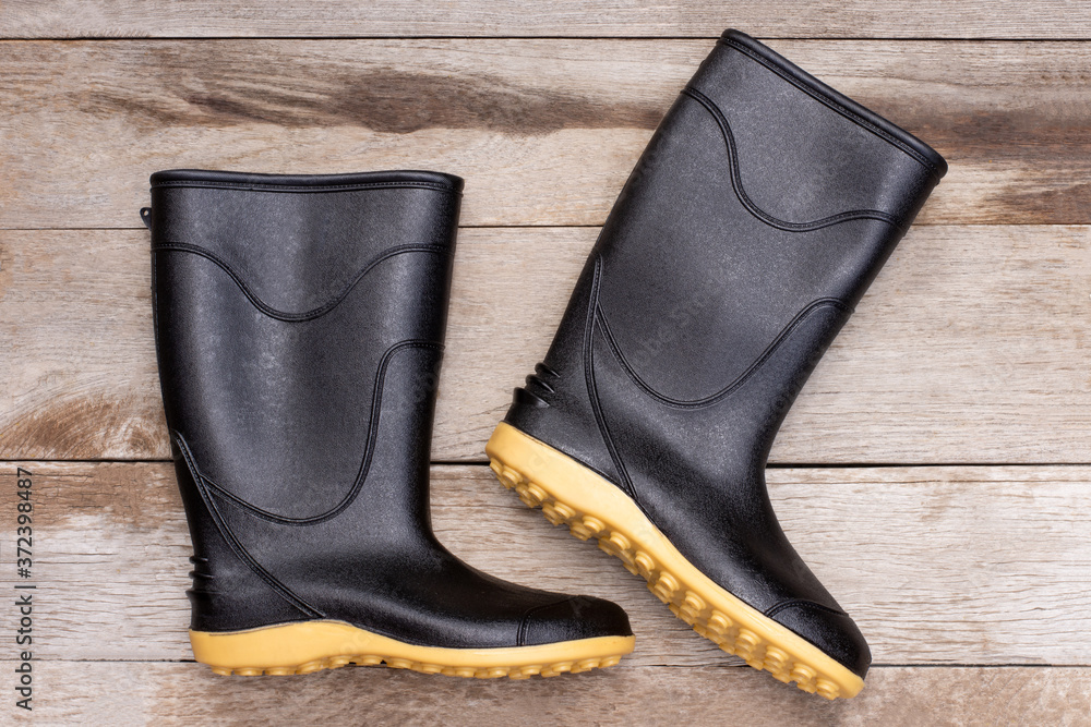 Black rubber boot ( galoshes ) isolated on wooden table background. Top view. Flat lay. Black rubber boot ( galoshes ) isolated on wooden table background. Top view. Flat lay.