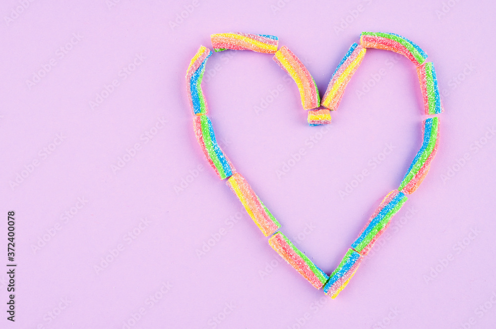 Heart shaped gummies on purple background.