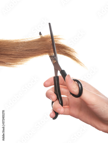 Female hand with hair and scissors on white background