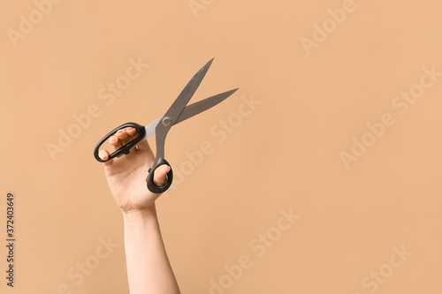 Female hand tailor's scissors on color background photo