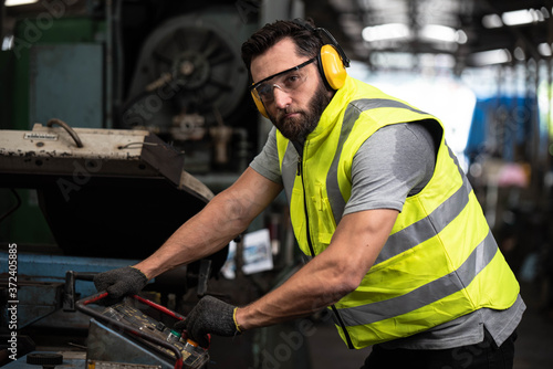 Portrait of technician man or industrial worker with hardhat or helmet, eye protection glasses, Tool and vest working electronic machinery on laptop and mechanical in Factory of manufacturing place