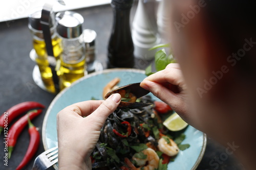 Black pasta with shrimps, mussels, and octopus. Appetizing food. Suggestion to serve the dish. Culinary photography.
