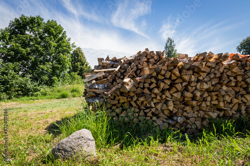 Stack of stacked firewood on a summer blue sky background