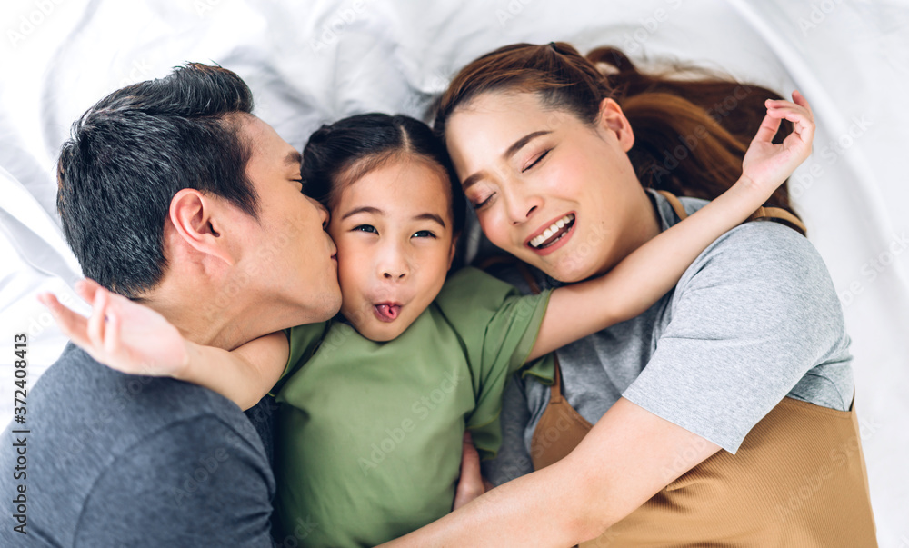 Top view of portrait enjoy happy smiling love asian family father and mother with young parents little asian girl looking at camera in moments good time lying on the floor at home