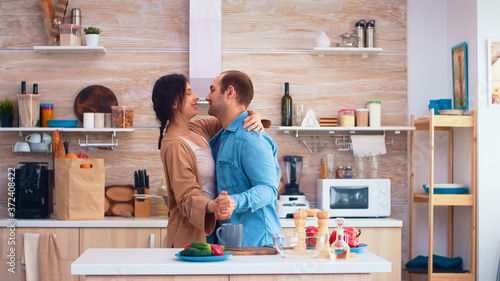 Tender couple dancing in kitchen and fresh vegetables on table. Cheerful happy young family together dance. Fun love affection romance leisure romantic music for enjoynment