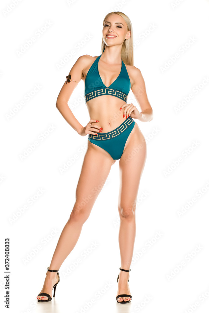Pretty young smiling lady in blue bikini swimsuit and sandals on white background Pretty young smiling lady in blue bikini swimsuit and sandals on white background