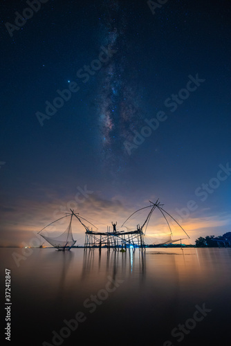 Landscape image of milky way over traditional square fishnet equipment at Pakpra Canal, Phatthalung, Thailand