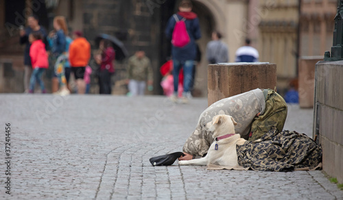 Beggar with dog begging for alms on the street in Prague