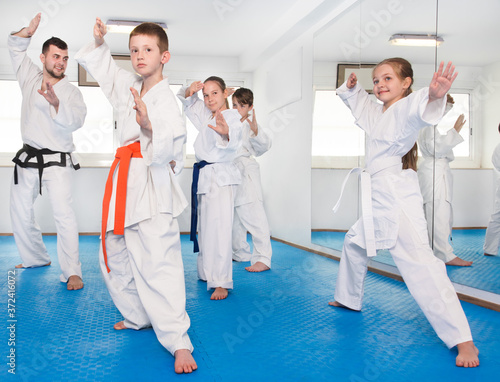 Children trying new martial moves in the practice during a karate class in a gym