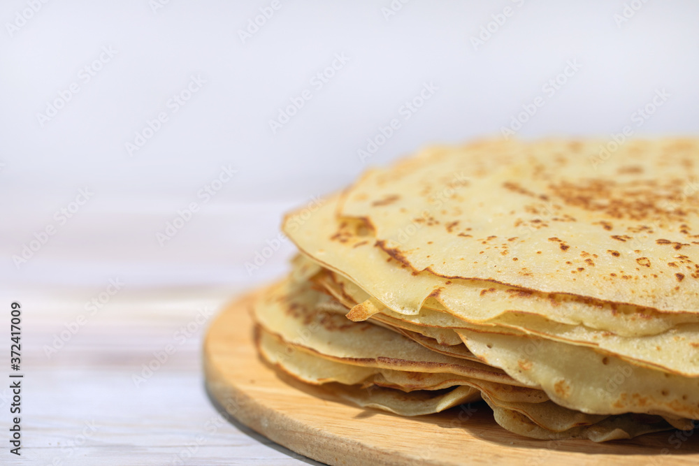 stack of fried pancakes on wooden plate on kitchen table. stack of fried pancakes on wooden plate on kitchen table.