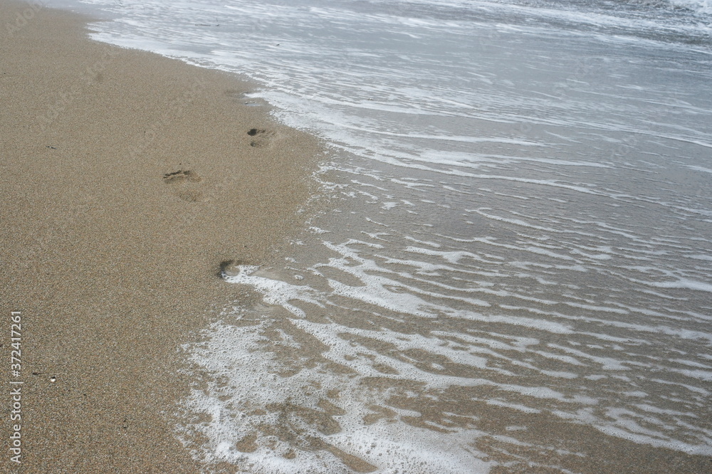 footprints in the wet sand by the sea