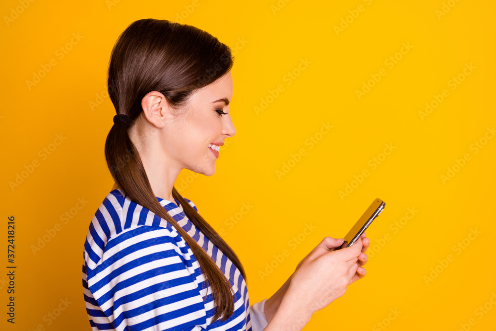 Close-up profile side view portrait of nice attractive pretty lovely cheerful focused brown-haired girl using device browsing web isolated on bright vivid shine vibrant yellow color background Close-up profile side view portrait of nice attractive pretty lovely cheerful focused brown-haired girl using device browsing web isolated on bright vivid shine vibrant yellow color background