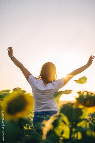 Back view of young woman's silhouette holding hands up in air and rejoice of beautiful sunset.
