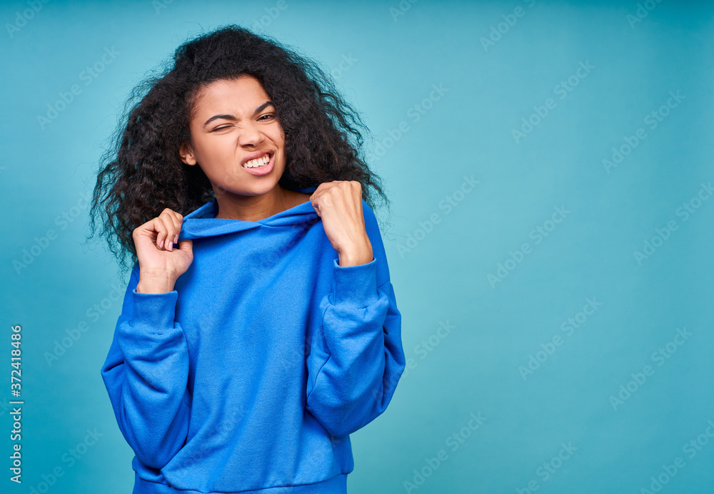 A funny teenage girl in a casual blue sweatshirt making grimaces. A funny teenage girl in a casual blue sweatshirt making grimaces.