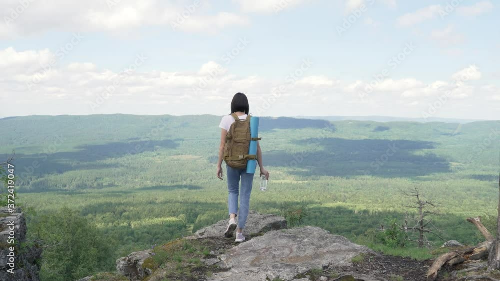 The girl climbs to the top of the mountain and slowly raises her hands. The girl climbs to the top of the mountain and slowly raises her hands.