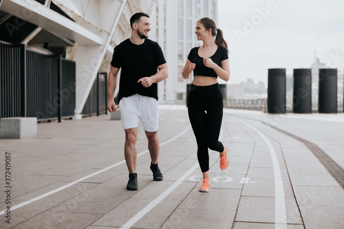 young couple handsome brunette man and beautiful woman in sportswear jogging on the street, everyday workout, athlete , healthy fit lifestyle