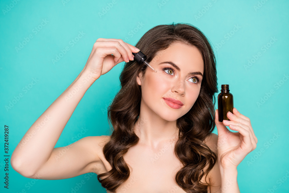 Fototapeta premium Closeup photo of beautiful naked lady wavy long hairdo hold professional cure serum bottle oil treatment cosmetologist pipette drop under eye isolated teal color background