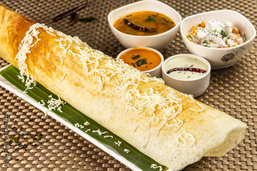 Cheese Masala dosa with different types of chutney and sambar. This is a closeup shot of one of the most famous Indian snack. photo