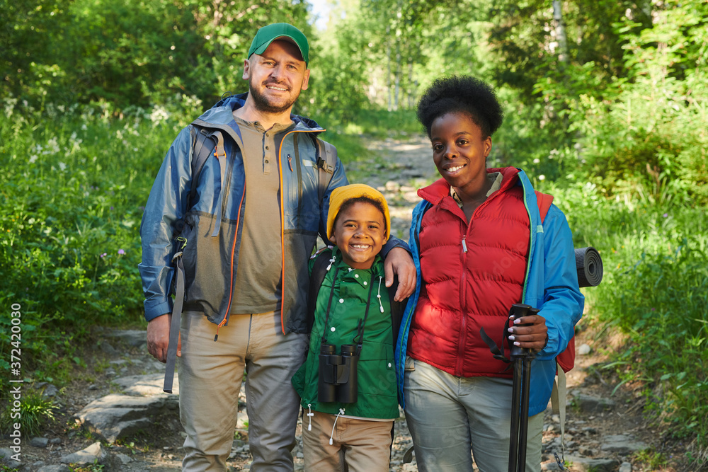 Portrait of happy family of tourists standing in the forest and smiling at camera Portrait of happy family of tourists standing in the forest and smiling at camera