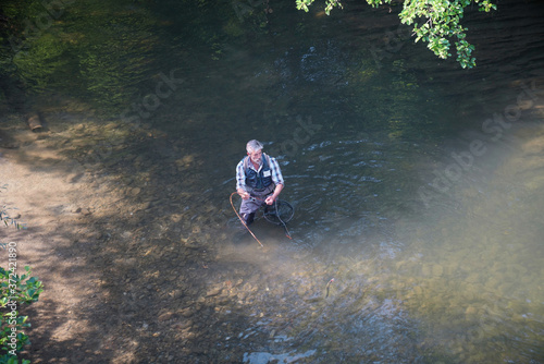 Man fly fishing in summer in a beautiful river with clear water catching a beautiful rainbow trout